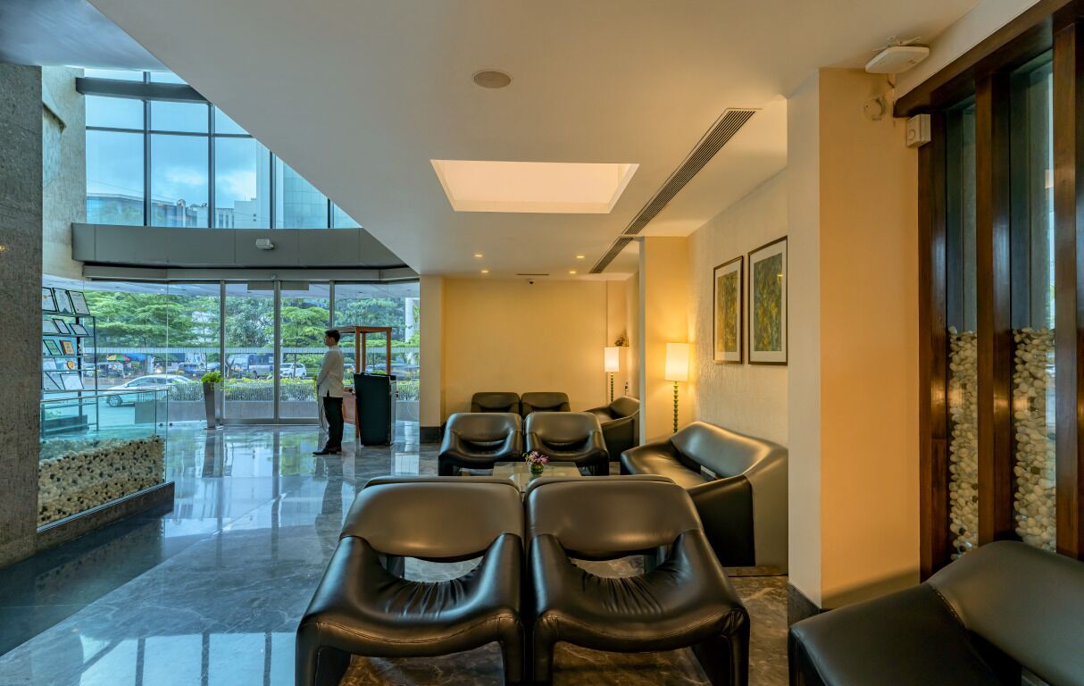 A modern hotel lobby with a glass wall, leather seating, and a view of the outdoors.