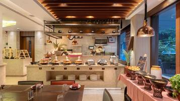 A modern dining area with a central buffet station, wooden ceiling, and large windows.