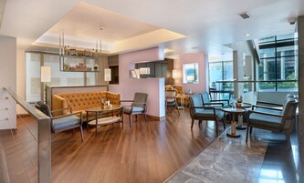 A modern hotel lobby with a plush sofa, dining area, and large windows offering views.
