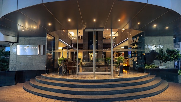 A modern hotel entrance with a curved facade, glass doors, and a staircase leading up to the entrance. - The Mirador Hotel, Mumbai International Airport (Mumbai)