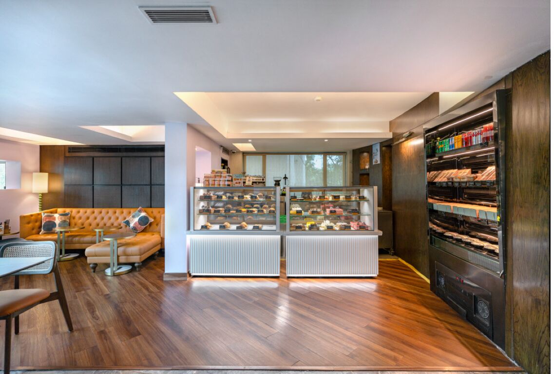 A modern interior with a wooden floor, a sofa, a display case with shoes, and a refrigerator.