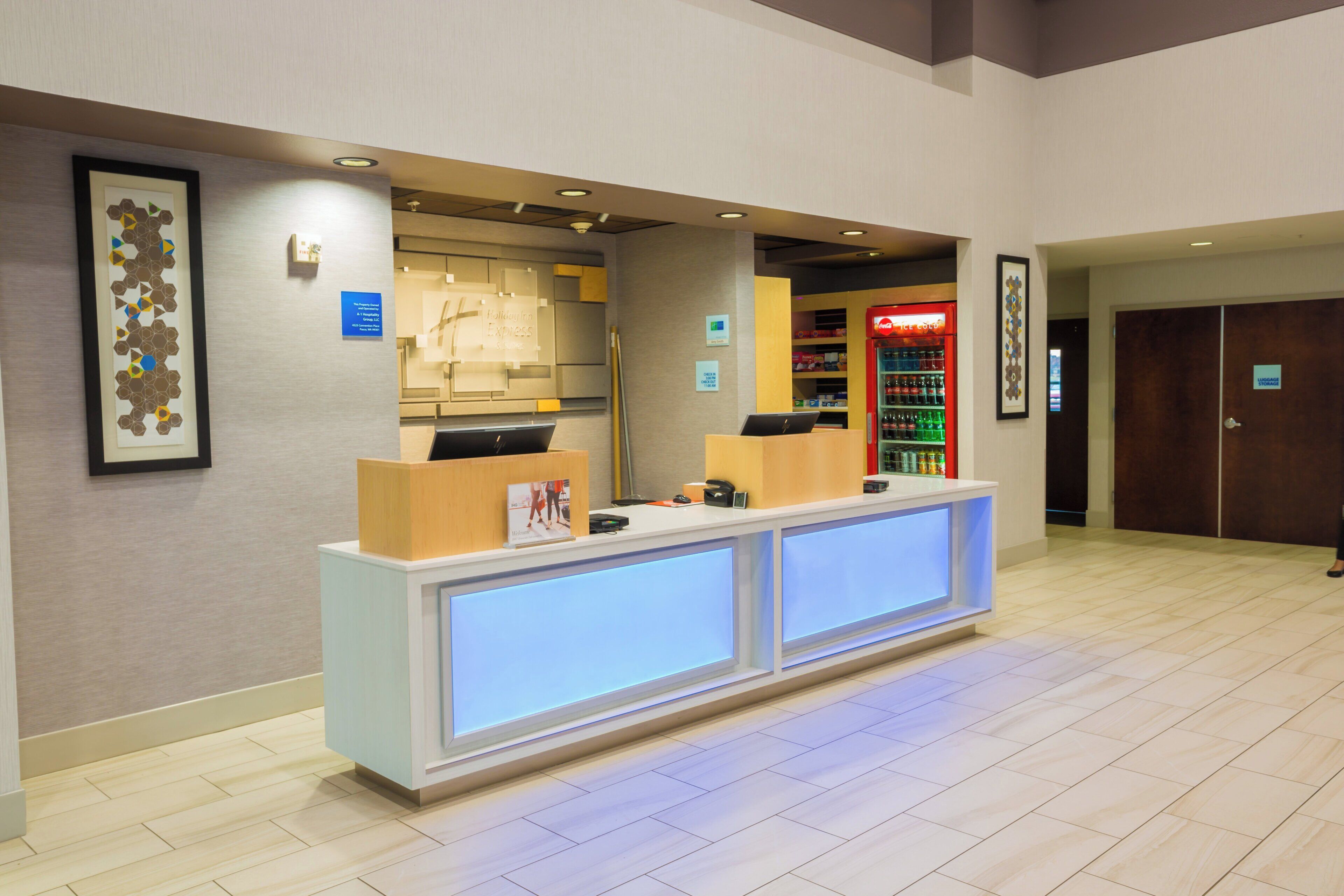 A hotel reception area with a reception desk, a Coca-Cola refrigerator, and a luggage storage sign.