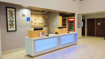 A hotel reception area with a reception desk, a Coca-Cola refrigerator, and a luggage storage sign.