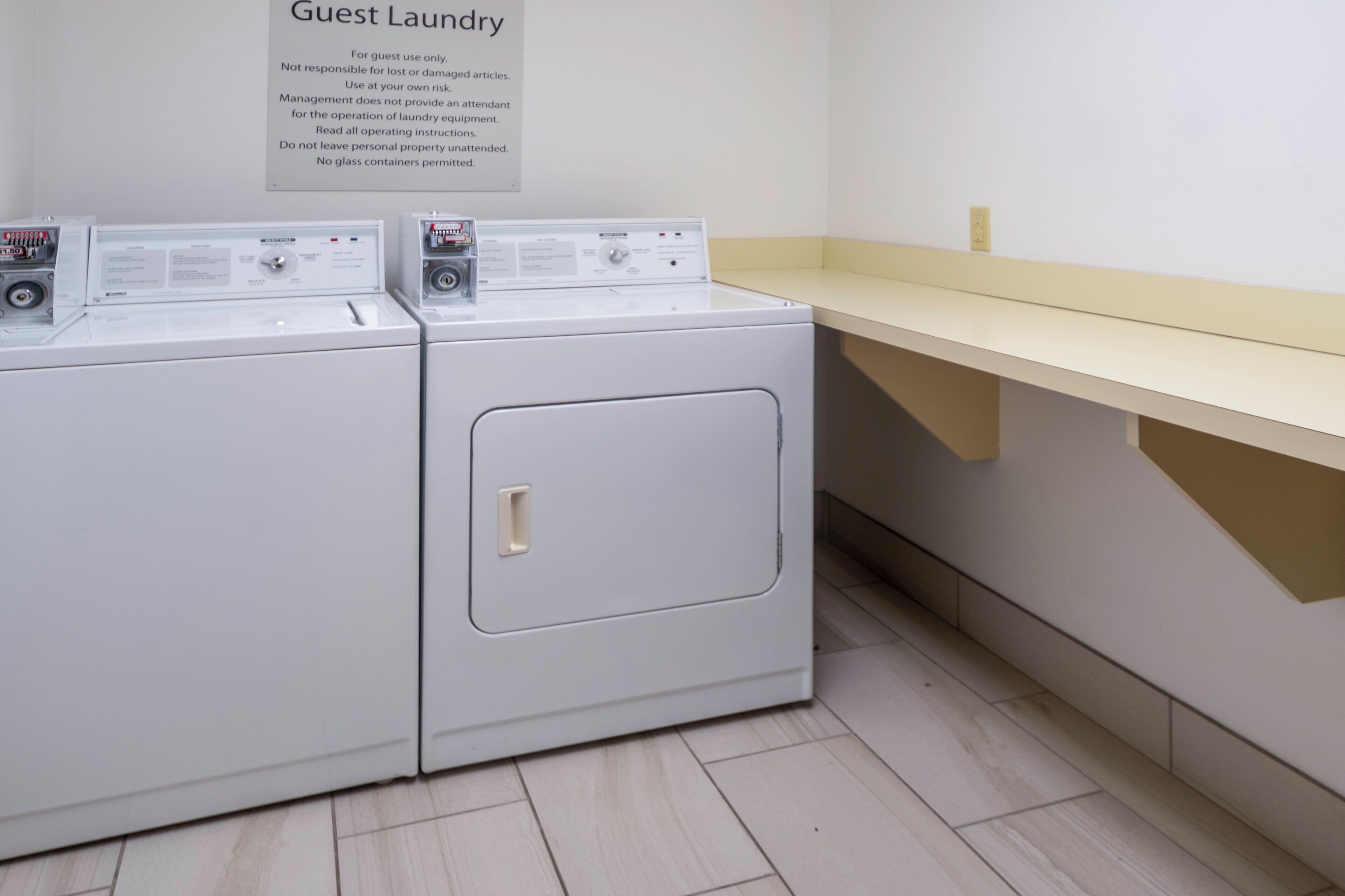 A guest laundry area with two washing machines and a sign with operating instructions.