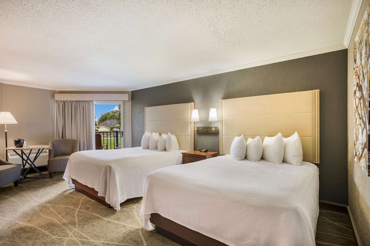 Ein Hotelzimmer mit zwei Betten, einem Schreibtisch und einem Stuhl.