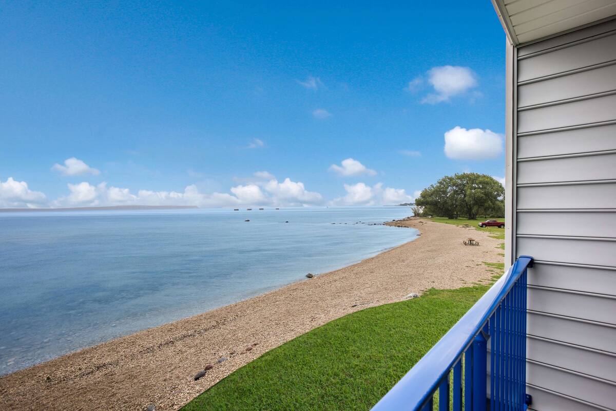 Blick auf den Strand vom Balkon, bewölkter Himmel und ruhige See.