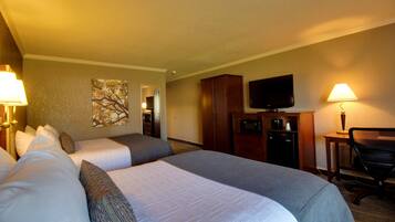 Una habitación de hotel con dos camas, televisión, escritorio y lámpara.