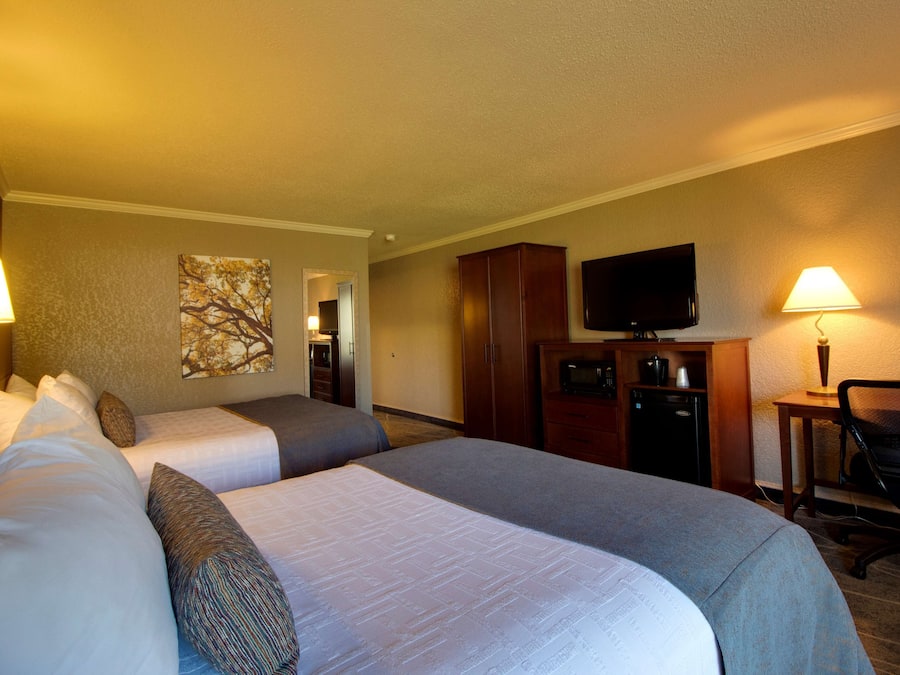 Una habitación de hotel con dos camas, televisión, escritorio y lámpara.