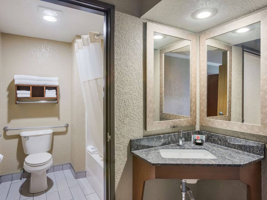 Un baño con inodoro, lavamanos, espejo y cortina de ducha.