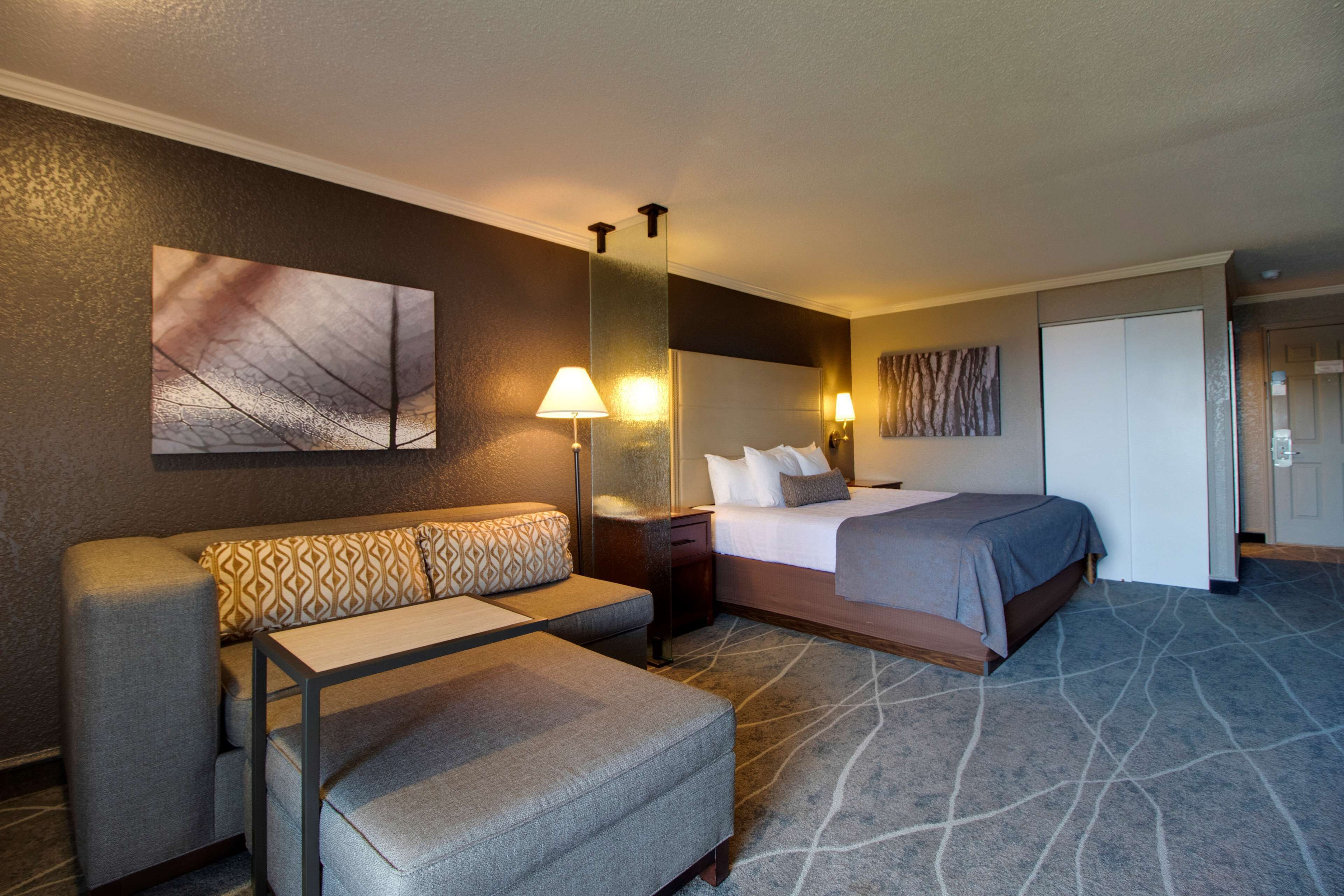 A hotel room with a bed, a sofa, a small table, and a nightstand.