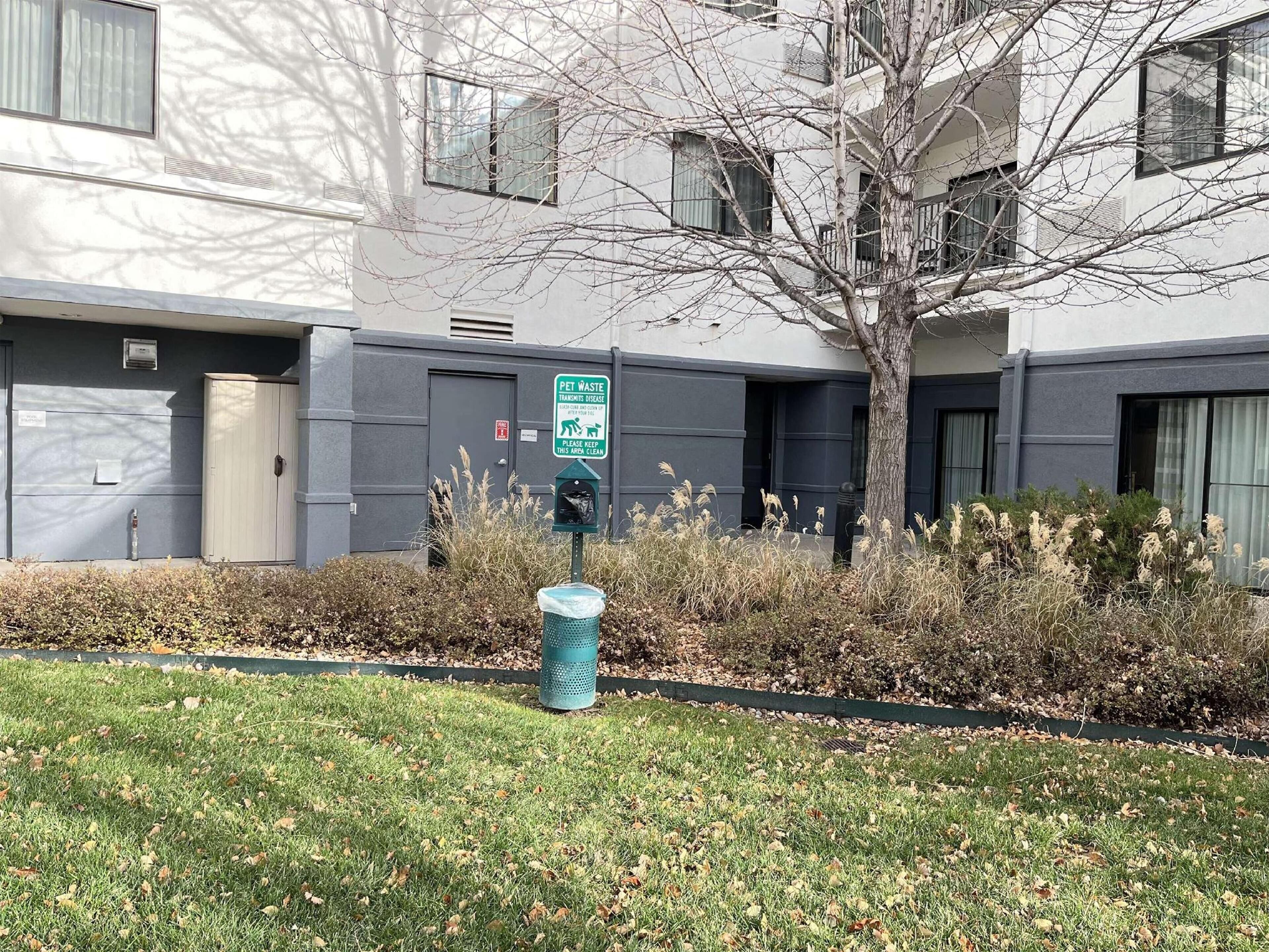 A building with a pet waste bin and a sign indicating a pet waste area.