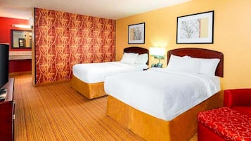 Ett hotellrum med två sängar, en röd soffa, en tv och konstverk på väggarna.