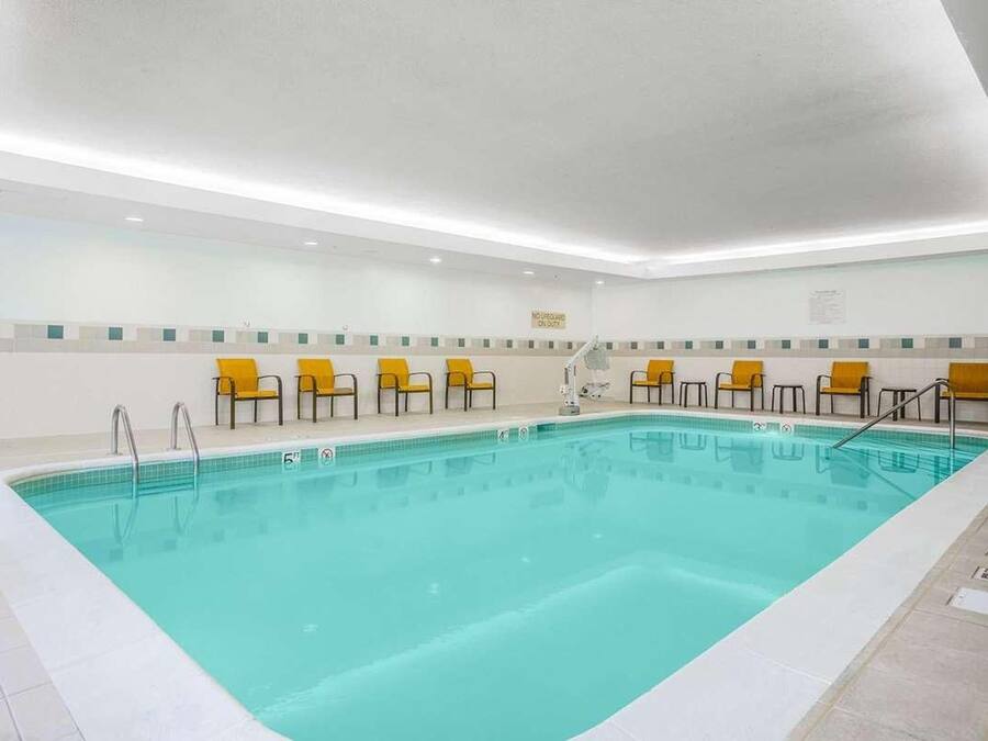 A swimming pool with yellow chairs and a no swimming sign.