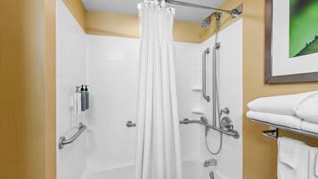 Une salle de bain moderne équipée d’une douche, de barres d’appui, d’un porte-serviettes et d’un tableau encadré au mur.