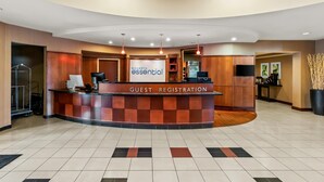 A hotel lobby with a guest registration desk, a reception area, and a seating area with a television.