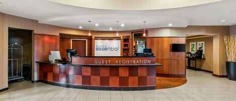 A hotel reception area with a guest registration desk, a refrigerator, and a television.
