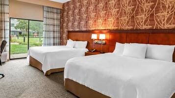 A hotel room with two beds, a large window, and a patterned wall.