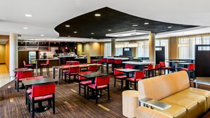 A modern hotel lobby with multiple seating areas, including tables and chairs, and a central seating area with a sofa.