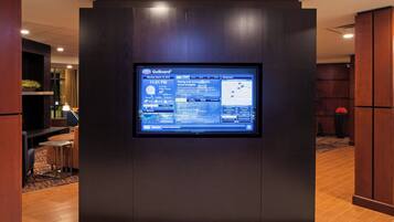 A GoBoard displaying weather and news information in a modern hotel lobby.