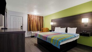 Una habitación de hotel con cama, mesitas de noche, escritorio, silla y cortina.