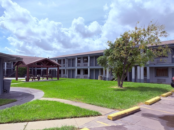 A multi-story building with a covered outdoor seating area and a well-maintained lawn.