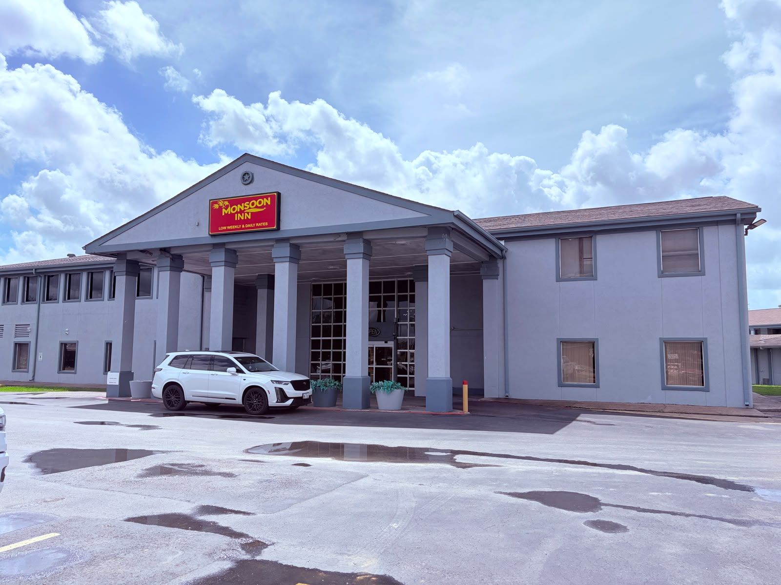 A motel with a covered entrance, a car parked in front, and a clear sky.