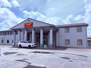 A motel with a covered entrance, a car parked in front, and a clear sky.