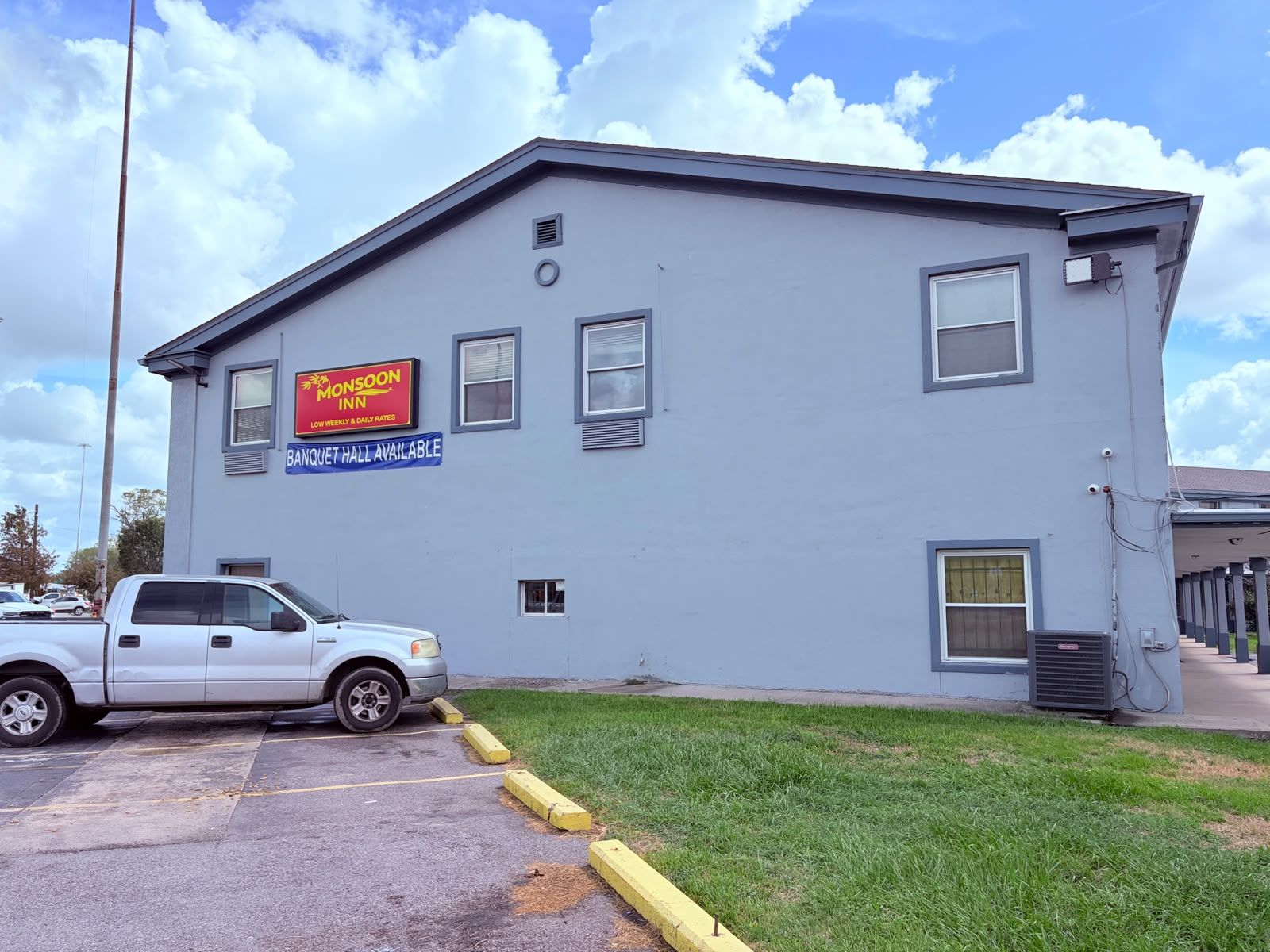 A two-story building with a sign for Monsoon Inn and a blue sign indicating a banquet hall is available.