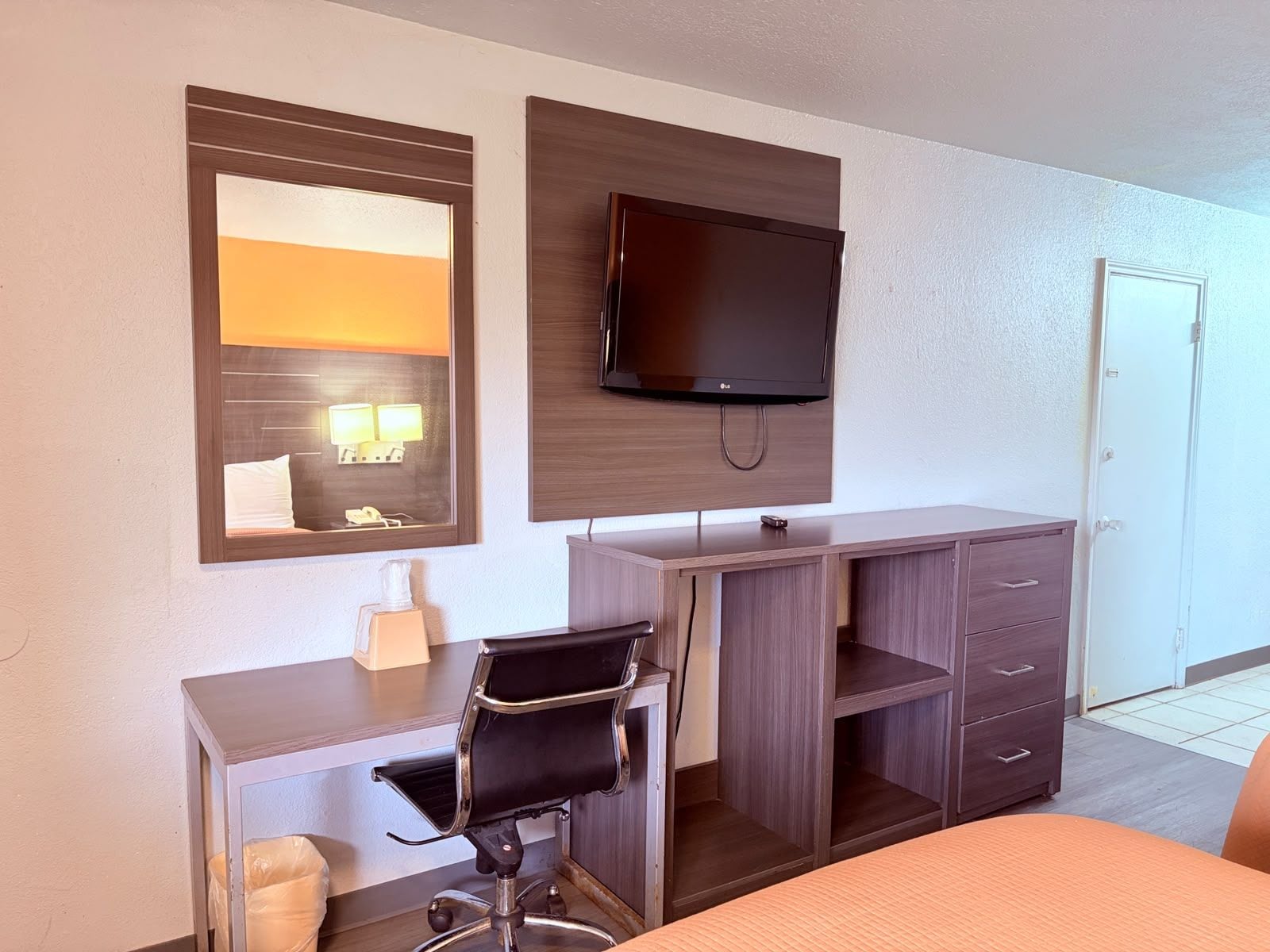 Une chambre d’hôtel comprenant un lit, un bureau avec une chaise, une télévision, un miroir et une armoire.