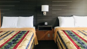 A hotel room with two beds, a nightstand with a lamp, and a telephone.