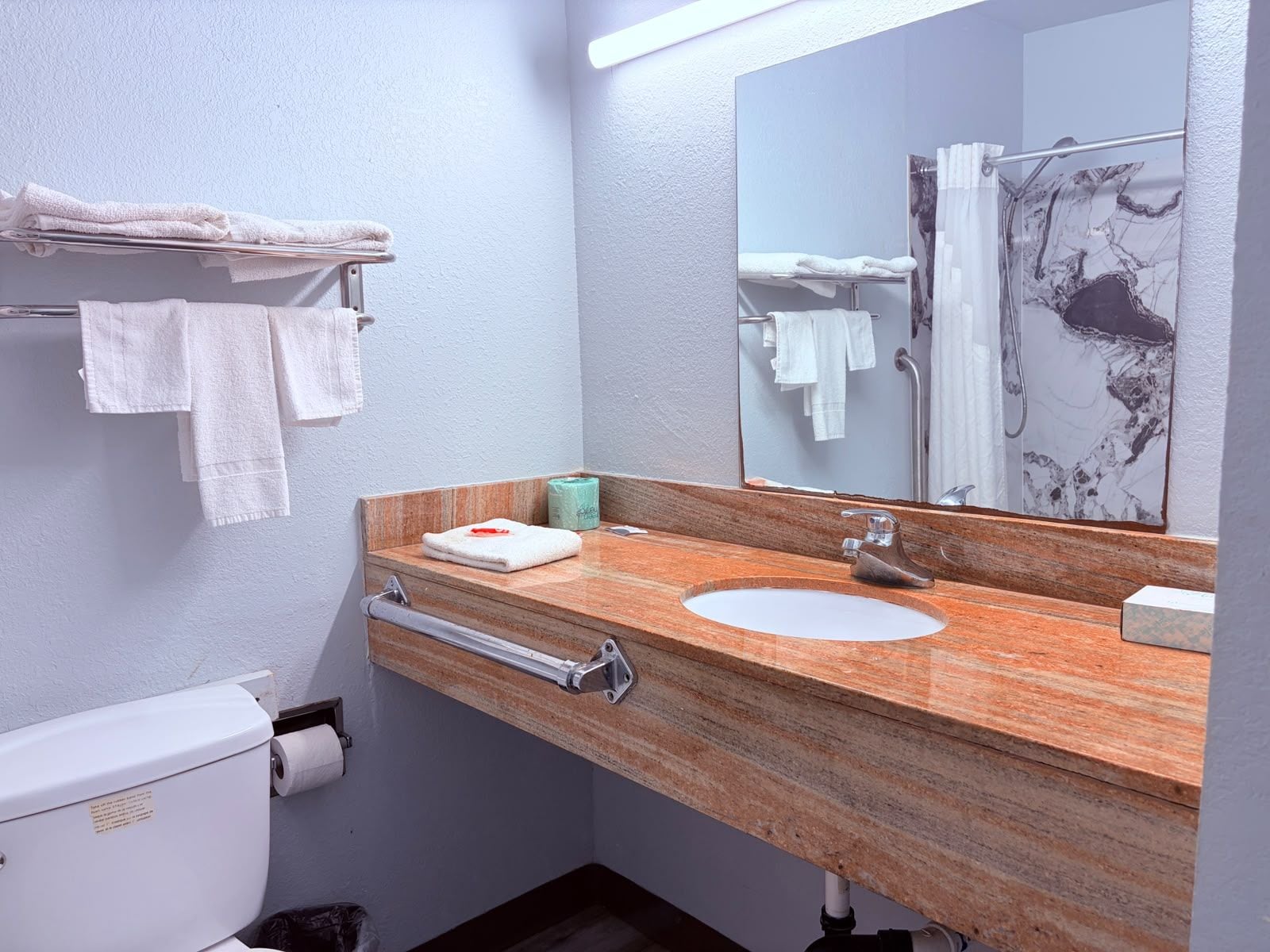 A bathroom with a marble sink, a mirror, a towel rack, and a toilet.