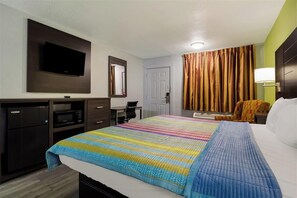 A hotel room with a bed, a desk, a flat-screen TV mounted on the wall, a microwave, and a door. -  Monsoon Inn (Beaumont)