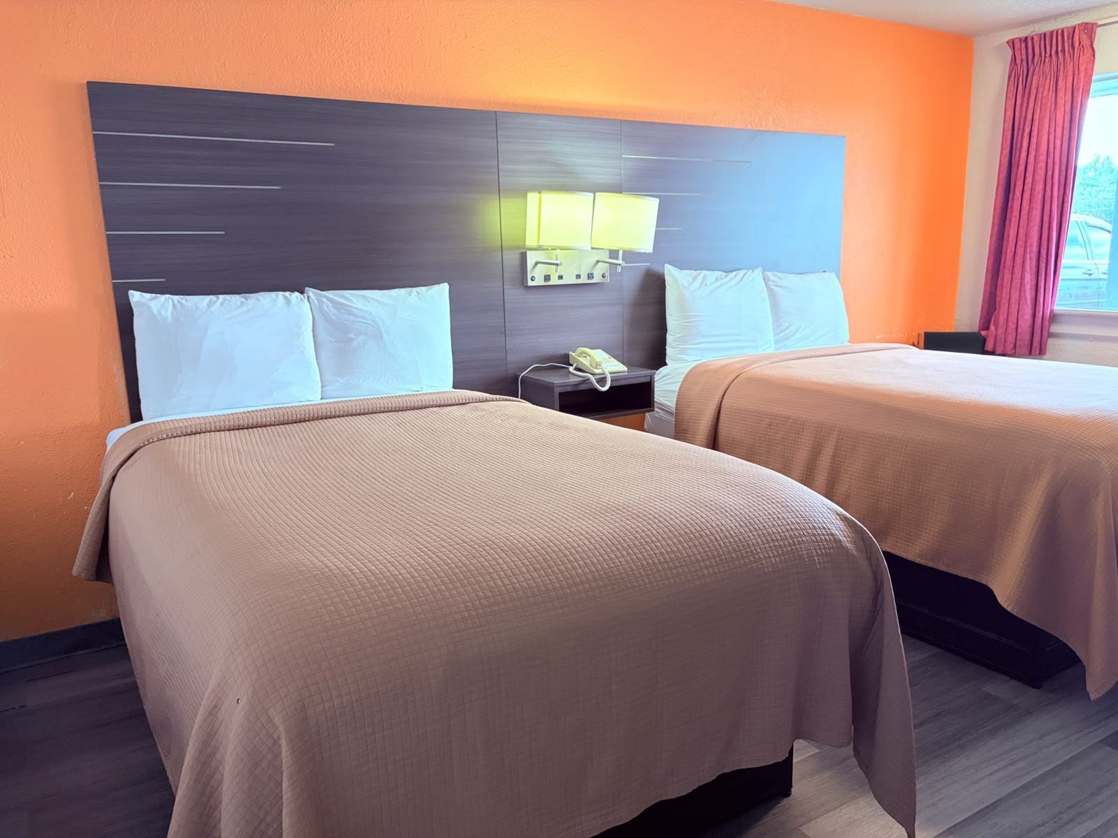 Una habitación de hotel con dos camas, una mesita de noche con una lámpara y un teléfono.