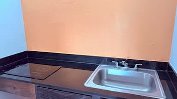 A kitchen with a black countertop, a stainless steel sink, and a built-in induction cooktop.