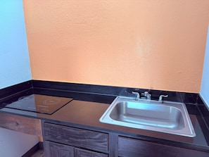 Una cocina con encimera negra, pileta de acero inoxidable y placa vitrocerámica integrada.