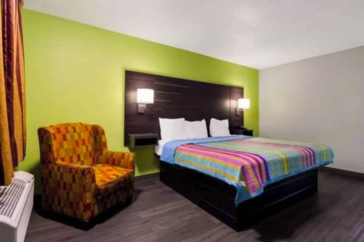 Una habitación de hotel con una cama, una silla y una mesita de noche.