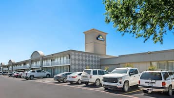A hotel with a Days Inn sign, a parking lot with several SUVs, and a building with a modern design.