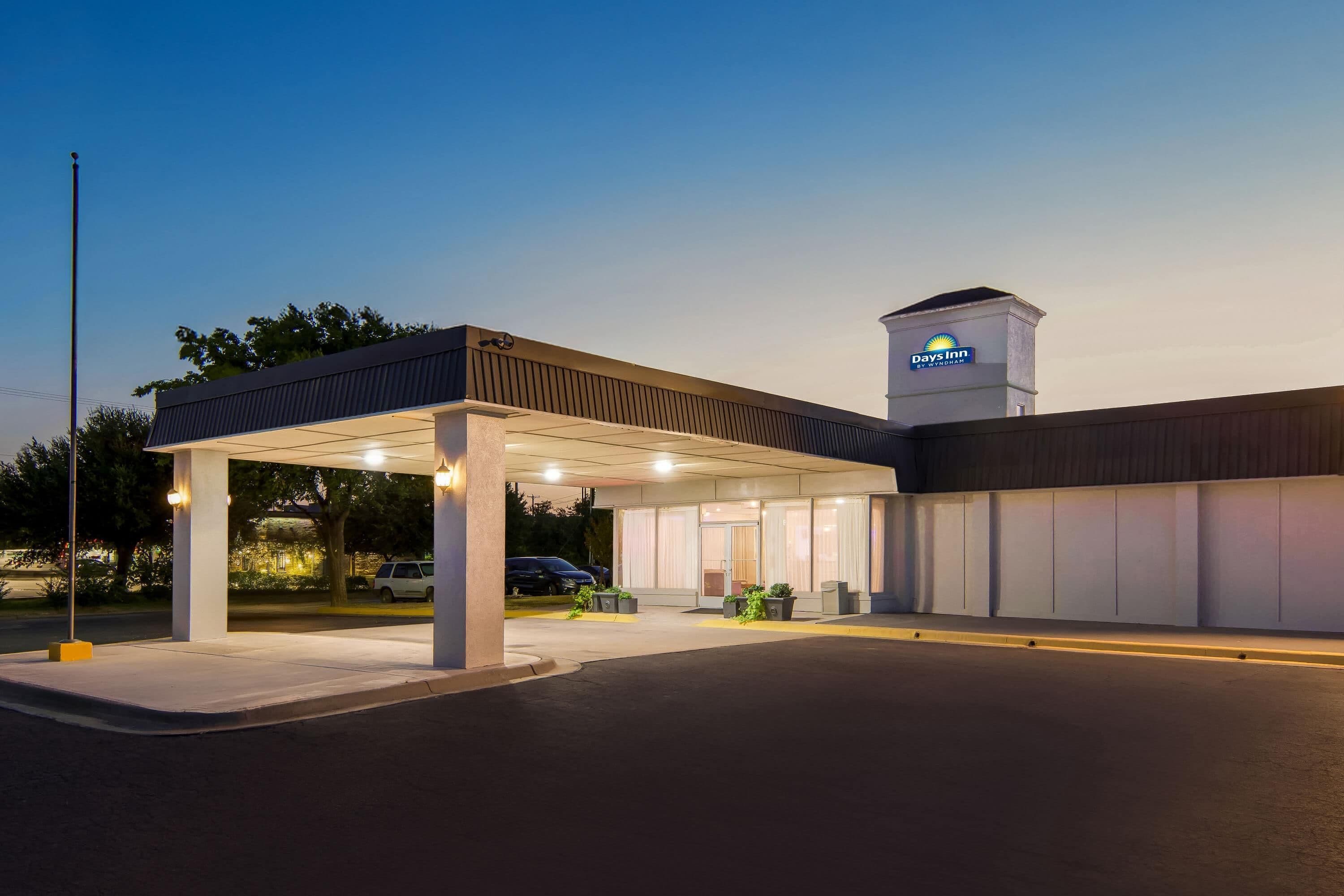 A Days Inn by Wyndham with a covered parking area and a standalone fuel pump.