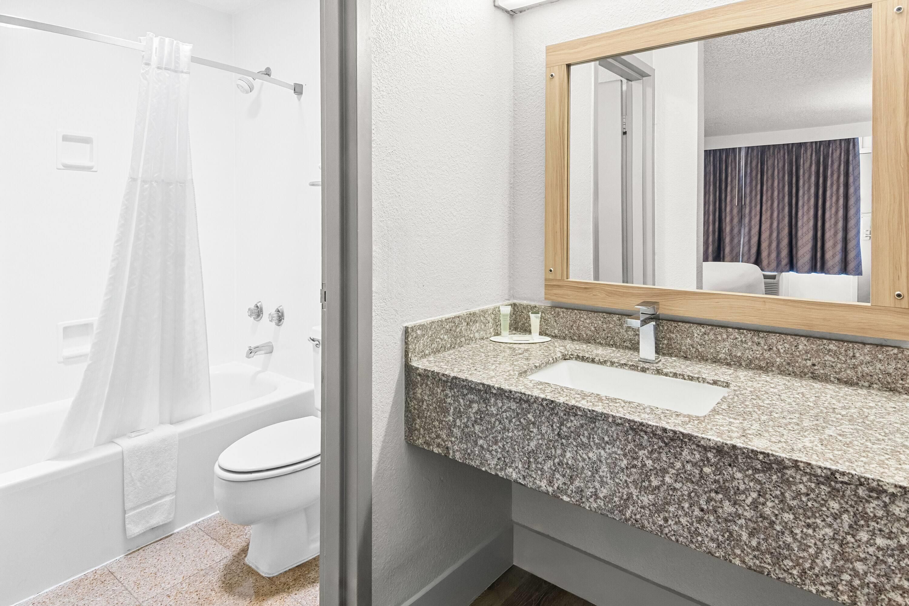 Ein Badezimmer mit Dusche, Toilette und Waschbecken mit einer Granit-Arbeitsplatte.
