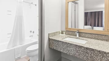 Un baño con ducha, inodoro y lavamanos con encimera de granito.