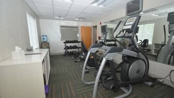 A gym with treadmills, dumbbells, and a desk with a tissue box.