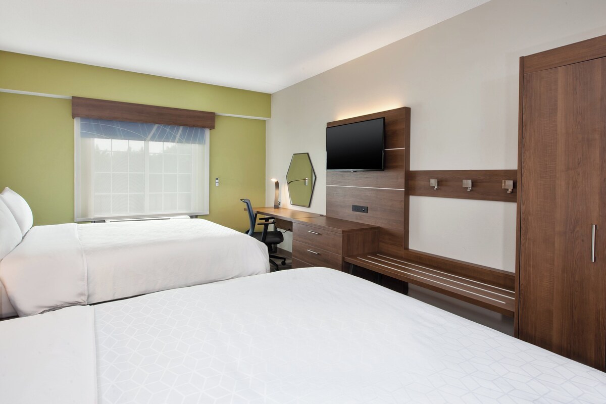 A hotel room with two beds, a desk, a TV, and a wardrobe.