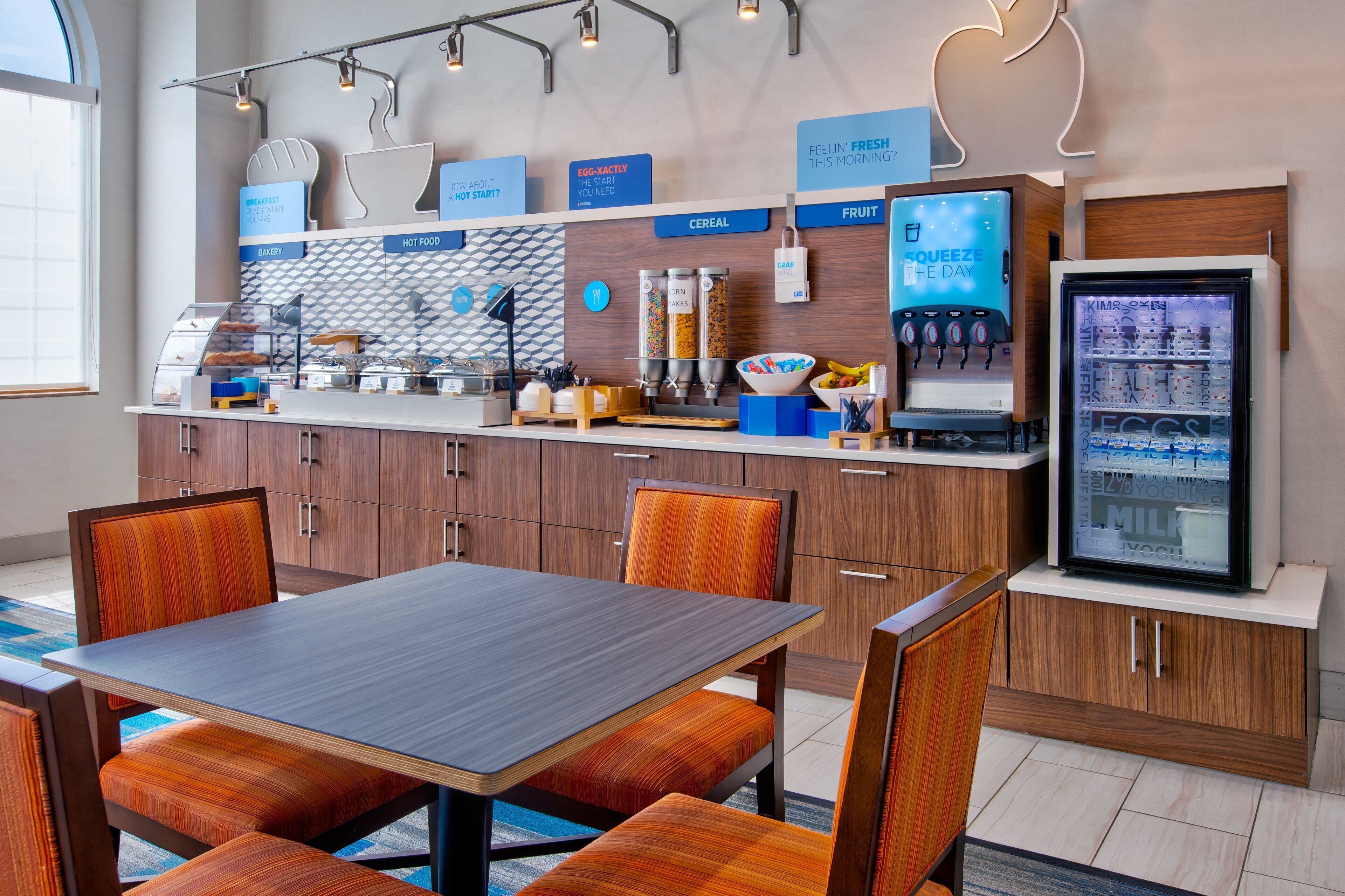 Een modern café met een houten toonbank, een zitgedeelte en een koelvitrine.