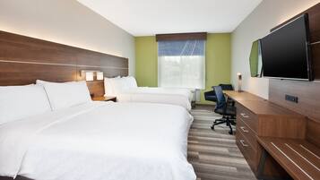 A hotel room with two beds, a desk, a chair, a television, and a window with blinds.