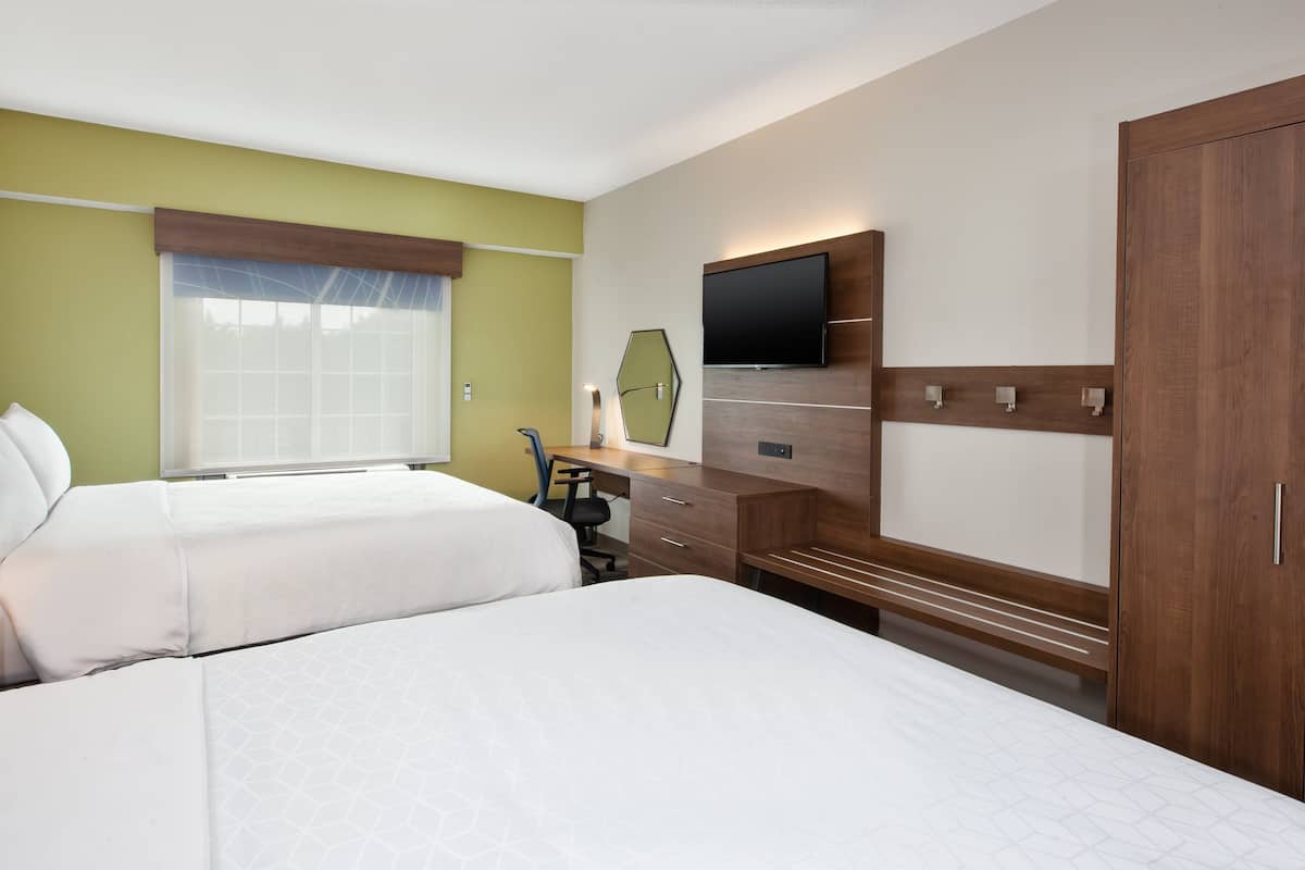 A hotel room with two beds, a desk, a TV, and a wardrobe.