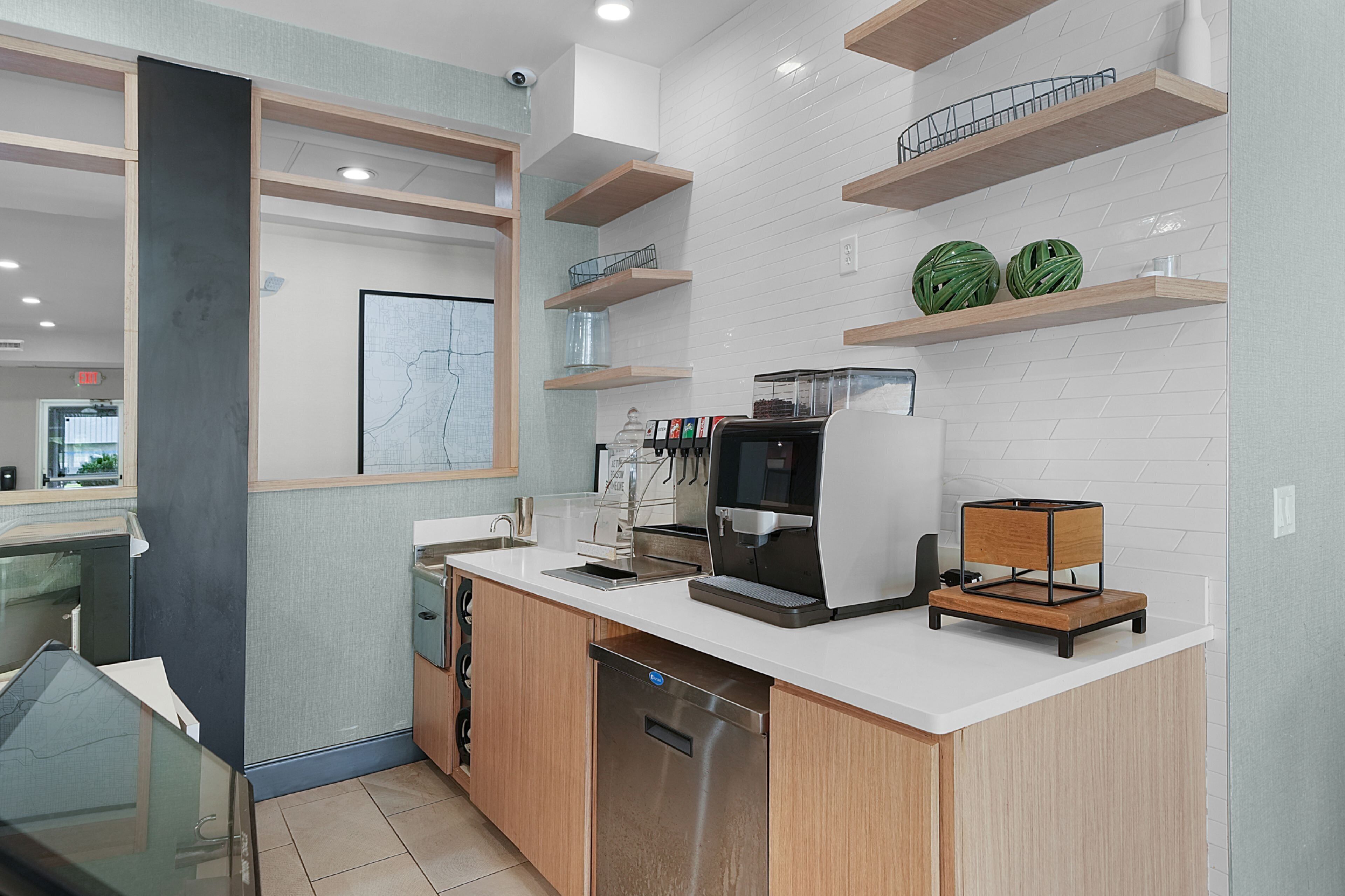 A modern kitchen with a coffee machine, a map on the wall, and wooden shelves.