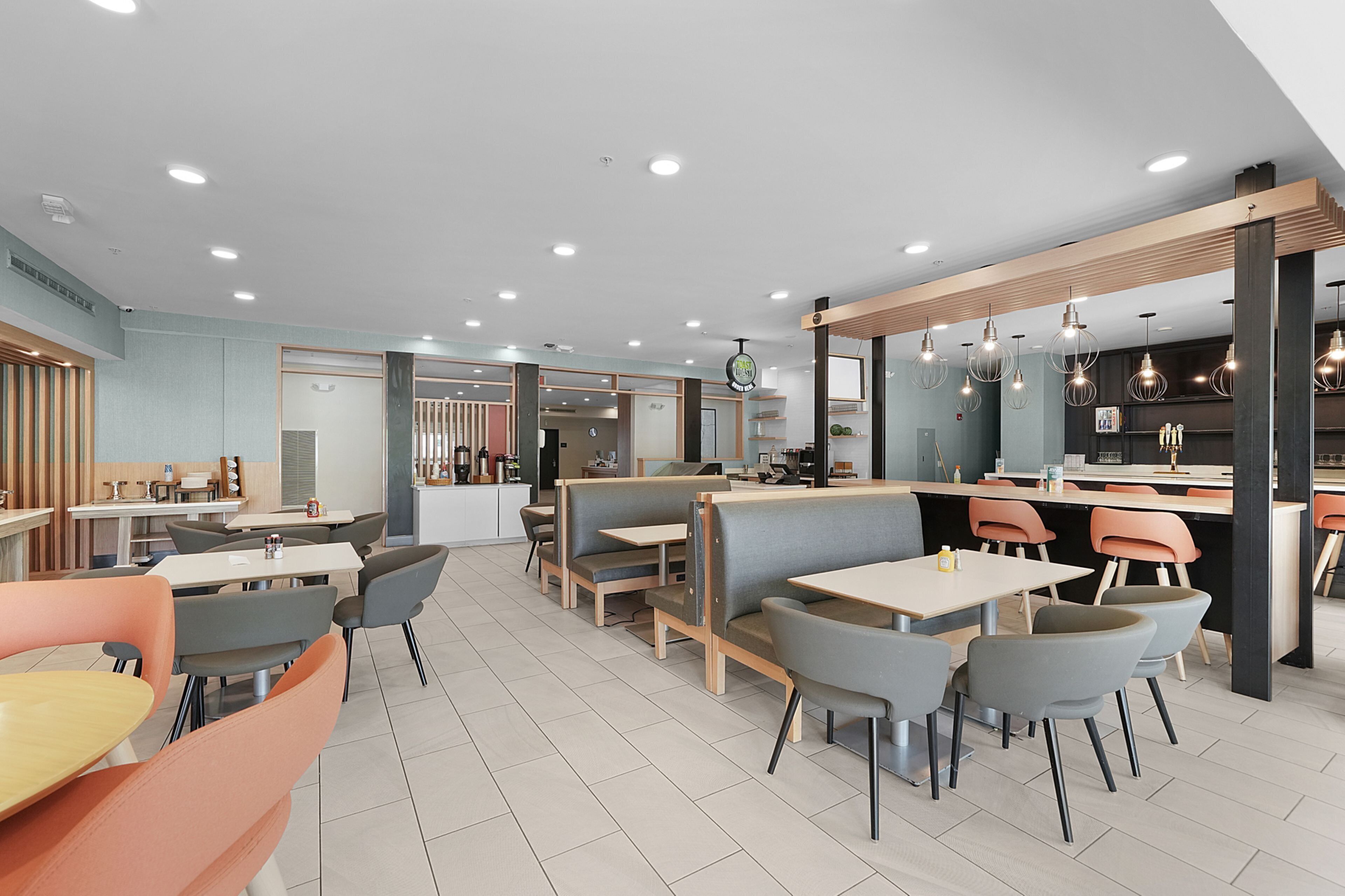 Un interior de restaurante moderno con cabinas, mesas y una zona de bar.