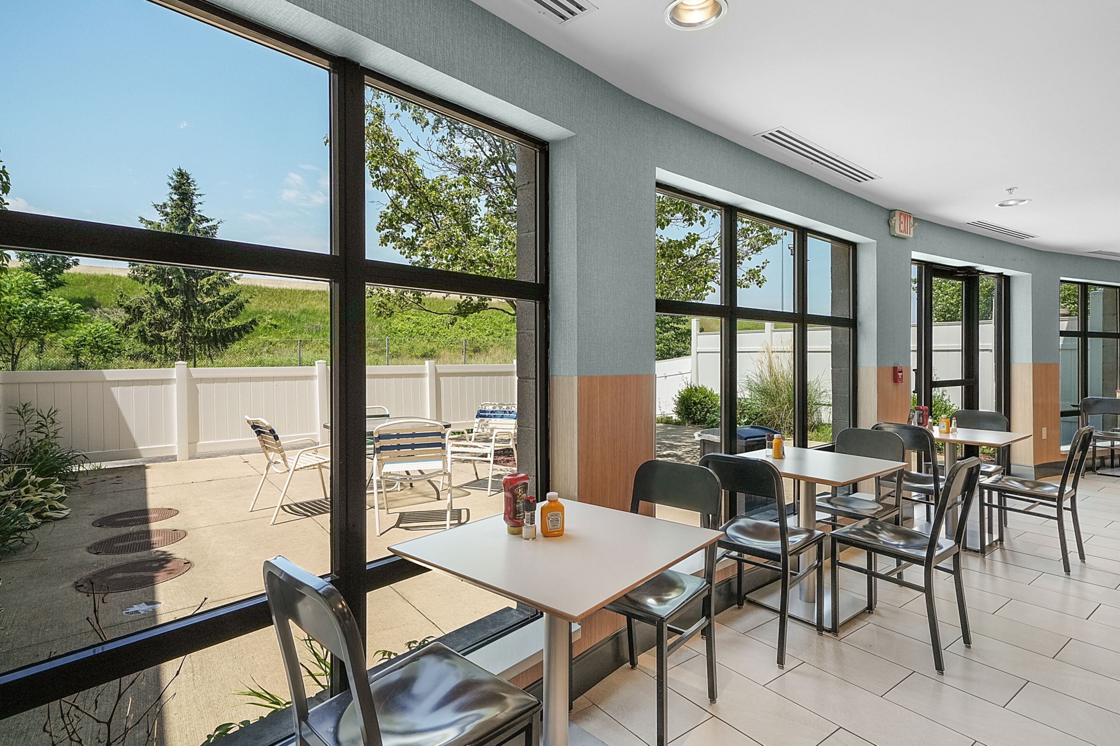 An indoor dining area with large windows, tables, and chairs.