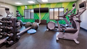 Un gimnasio con cintas de correr, elípticas y pesas sueltas.