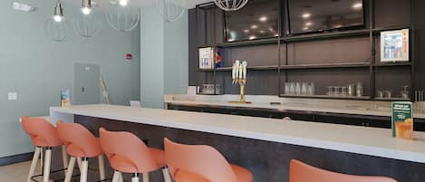 A modern bar area with a counter, bar stools, and overhead lighting.